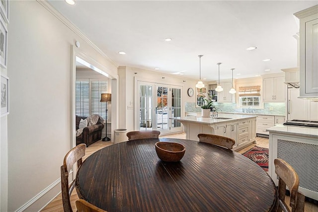 dining space with ornamental molding, light hardwood / wood-style floors, and sink