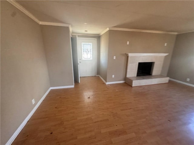 unfurnished living room with hardwood / wood-style flooring, ornamental molding, and a fireplace