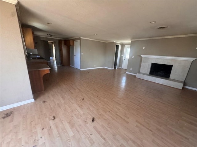 unfurnished living room featuring light hardwood / wood-style floors, crown molding, and a fireplace