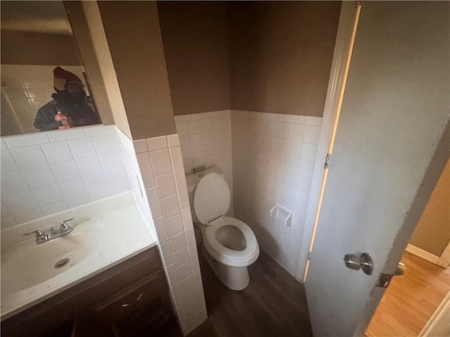 bathroom with vanity, toilet, wood-type flooring, and tile walls