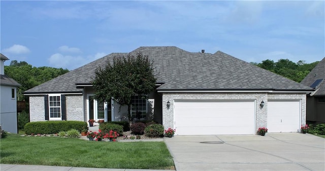 single story home featuring a garage, driveway, a front lawn, and brick siding