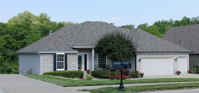 ranch-style house featuring a garage, brick siding, driveway, and roof with shingles