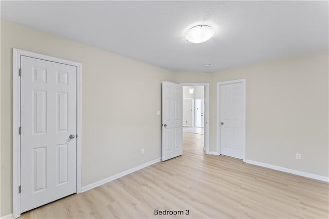 unfurnished room with light wood-style flooring and baseboards