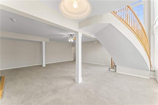 finished below grade area with light colored carpet, ceiling fan, baseboards, and stairs