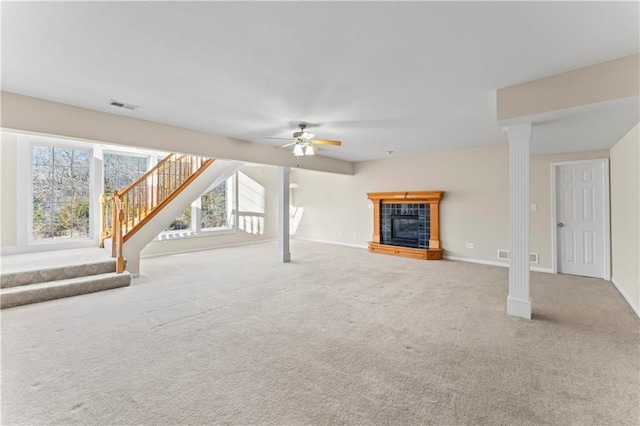 unfurnished living room featuring carpet floors, a fireplace, visible vents, stairway, and a ceiling fan