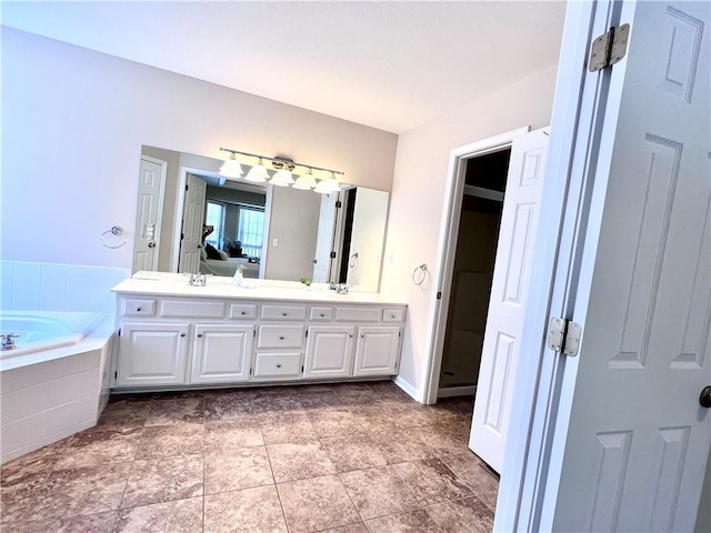 ensuite bathroom with double vanity, a sink, a bath, and ensuite bathroom