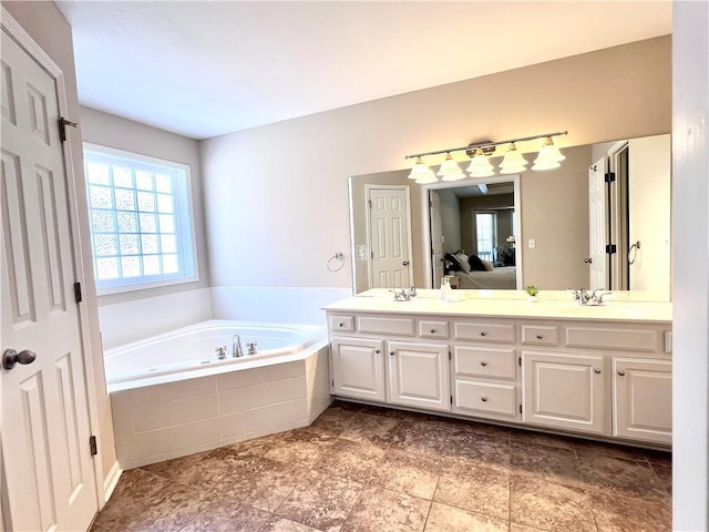 ensuite bathroom with double vanity, ensuite bath, a sink, and a bath