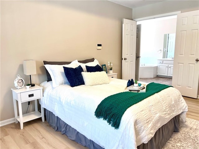 bedroom featuring light wood-style floors, connected bathroom, and baseboards