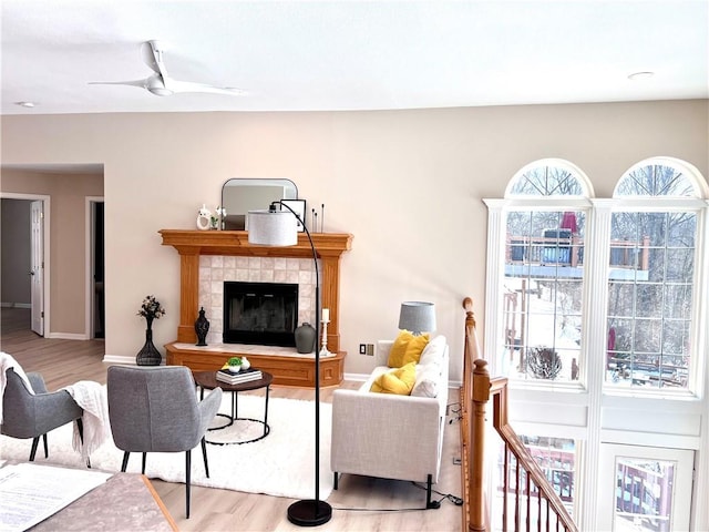 living room featuring light wood-type flooring, ceiling fan, and baseboards