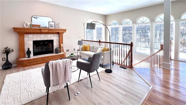 living room with light wood finished floors, baseboards, visible vents, and a tiled fireplace