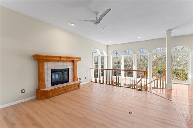 unfurnished living room featuring light wood-type flooring, baseboards, a ceiling fan, and a tile fireplace