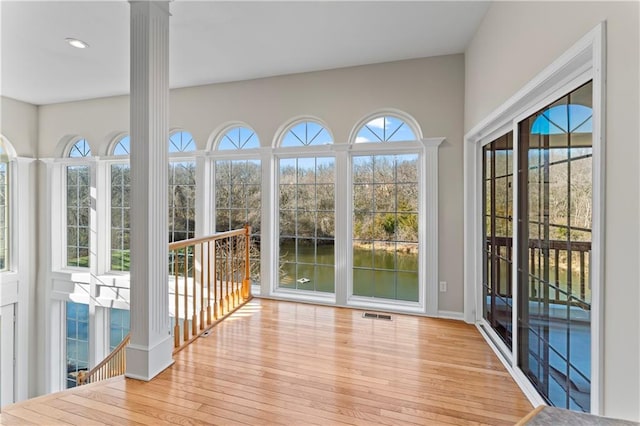 unfurnished sunroom with plenty of natural light, decorative columns, and visible vents