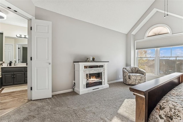 bedroom with vaulted ceiling, carpet floors, and ensuite bath