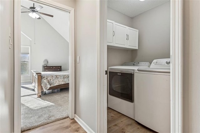 washroom with washing machine and clothes dryer, ceiling fan, cabinets, light hardwood / wood-style floors, and a textured ceiling