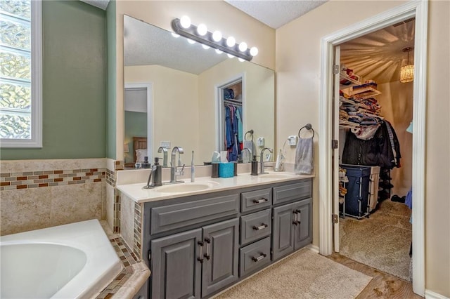 bathroom with hardwood / wood-style floors, vanity, and tiled bath