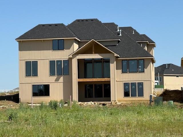 rear view of property featuring roof with shingles