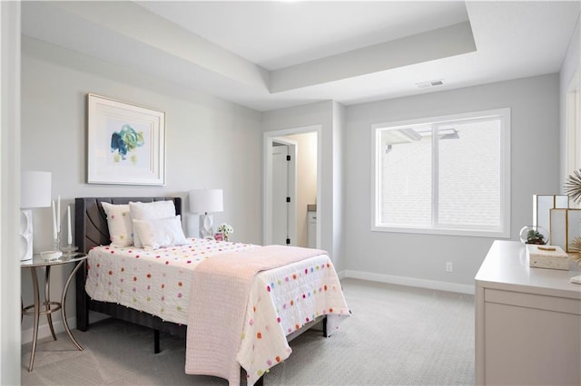 bedroom featuring baseboards, light colored carpet, and a raised ceiling