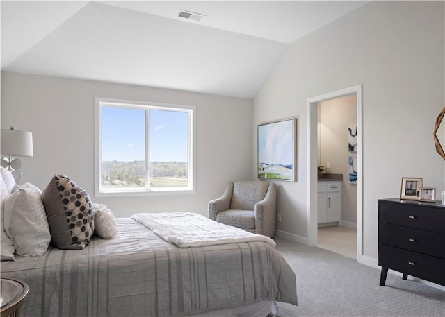 bedroom with light colored carpet, vaulted ceiling, baseboards, and ensuite bathroom