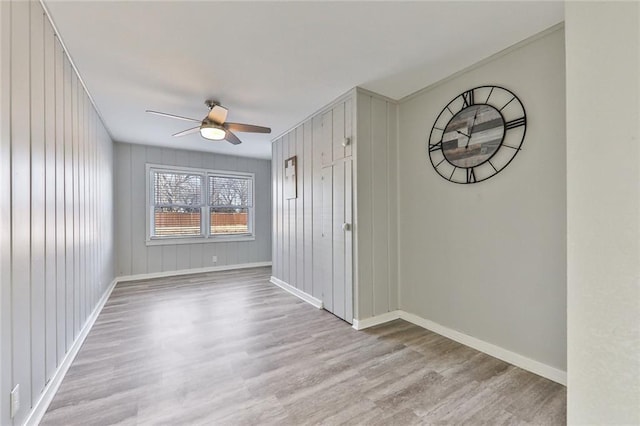 spare room featuring ceiling fan, wood walls, and light wood-type flooring