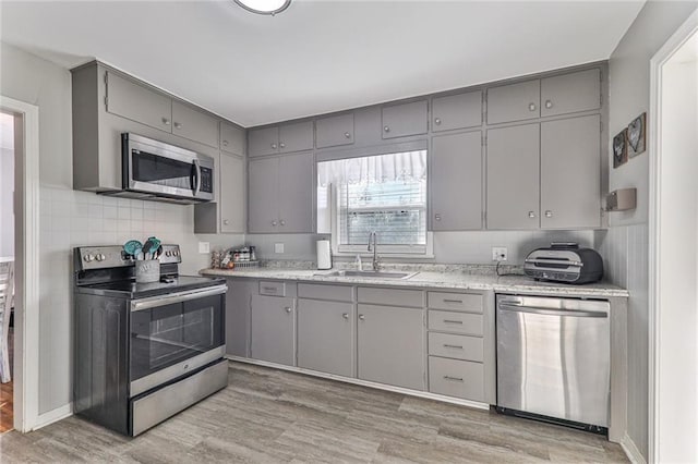 kitchen with stainless steel appliances, light hardwood / wood-style flooring, gray cabinetry, and sink