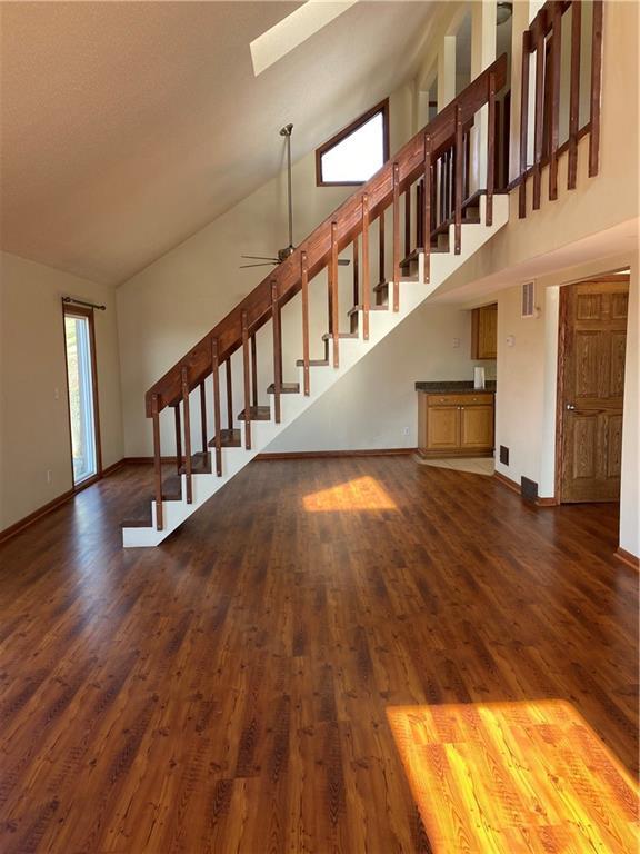 unfurnished living room featuring ceiling fan, high vaulted ceiling, and dark wood-type flooring