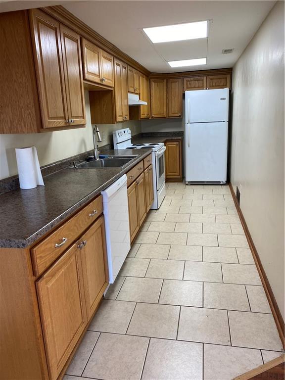 kitchen featuring white appliances, sink, and light tile patterned floors