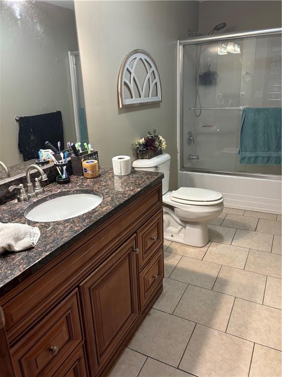 full bathroom with tile patterned floors, vanity, bath / shower combo with glass door, and toilet