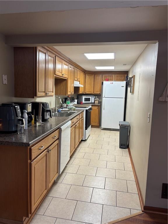 kitchen featuring light tile patterned flooring, white appliances, and sink