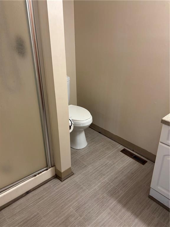 bathroom featuring vanity, an enclosed shower, and toilet