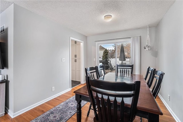 dining room with hardwood / wood-style flooring and a textured ceiling