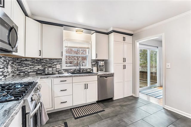 kitchen featuring white cabinetry, stainless steel appliances, sink, backsplash, and light stone counters