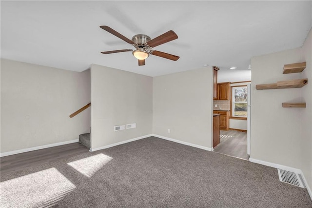 unfurnished living room featuring ceiling fan and dark wood-type flooring