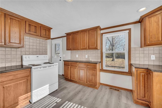 kitchen featuring tasteful backsplash, white range with electric stovetop, dark stone counters, light hardwood / wood-style floors, and ornamental molding