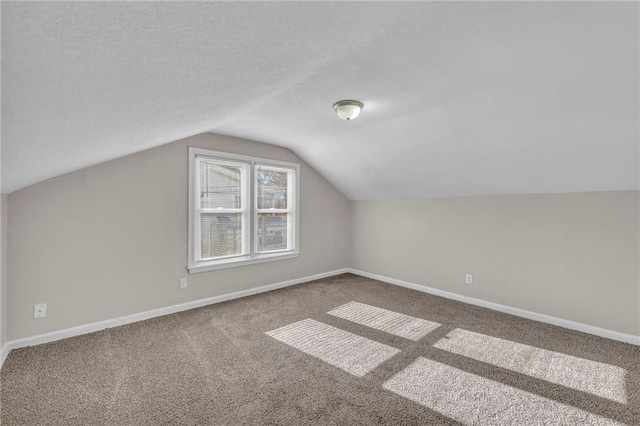 additional living space with carpet flooring, a textured ceiling, and vaulted ceiling