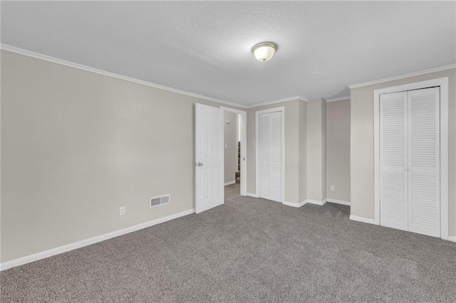 unfurnished bedroom with carpet floors, a textured ceiling, and ornamental molding