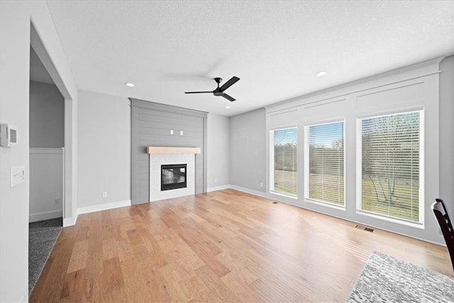 unfurnished living room featuring a textured ceiling, light hardwood / wood-style flooring, and ceiling fan