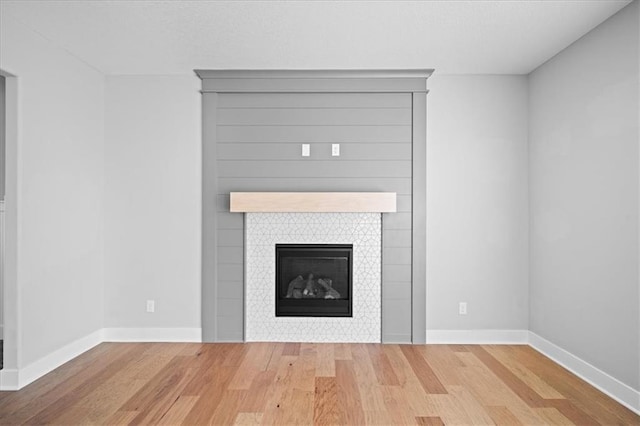 interior details featuring wood-type flooring and a tile fireplace