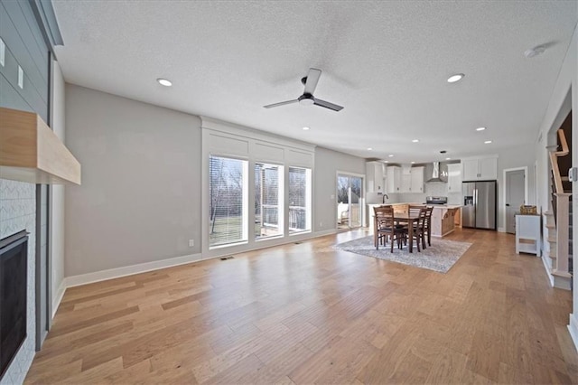 unfurnished living room with a fireplace, a textured ceiling, and light wood-type flooring