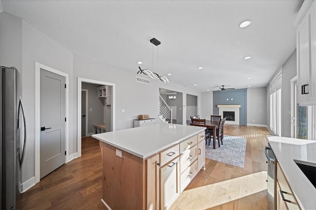 kitchen with a kitchen island, light hardwood / wood-style floors, white cabinetry, hanging light fixtures, and stainless steel refrigerator