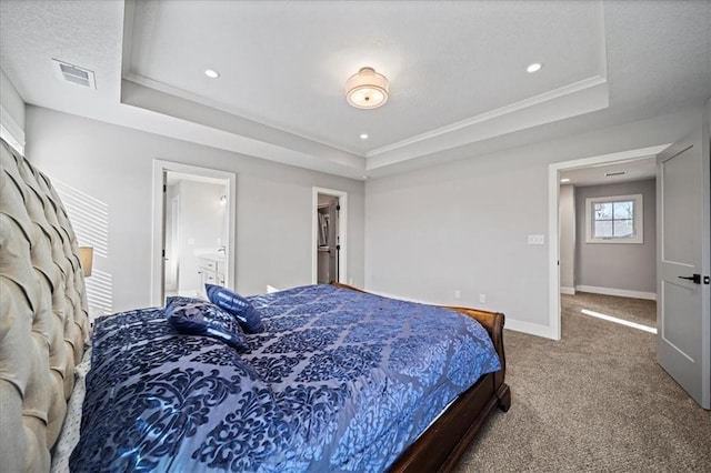 carpeted bedroom with a raised ceiling, crown molding, and ensuite bath