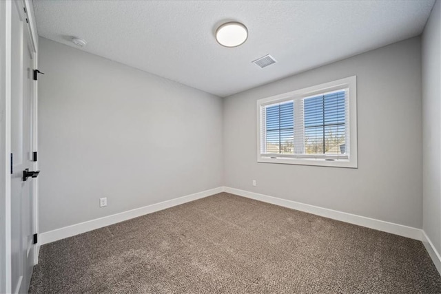 spare room featuring carpet flooring and a textured ceiling