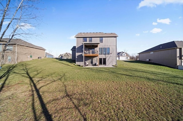 rear view of house with a lawn and a balcony