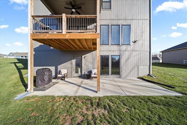 back of house featuring a lawn, ceiling fan, a deck, and a patio