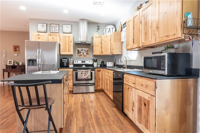 kitchen featuring appliances with stainless steel finishes, light brown cabinetry, and wall chimney exhaust hood