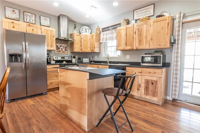 kitchen with stainless steel appliances, a wealth of natural light, wall chimney exhaust hood, and a breakfast bar area