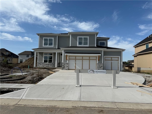 12404 W 184th St, Overland Park, KS 66013 - view of front of house featuring driveway, a porch, an attached garage, and stone siding
