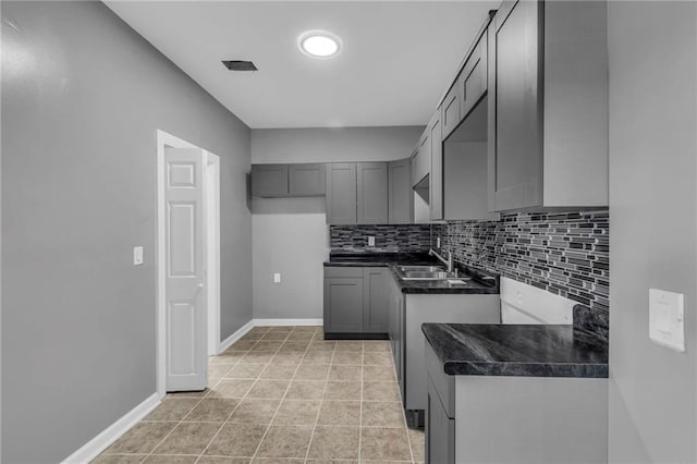 kitchen with light tile patterned flooring, tasteful backsplash, gray cabinetry, and sink