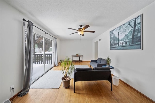 living room with a textured ceiling, ceiling fan, and hardwood / wood-style floors