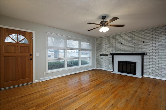 unfurnished living room featuring hardwood / wood-style flooring, ceiling fan, and a fireplace