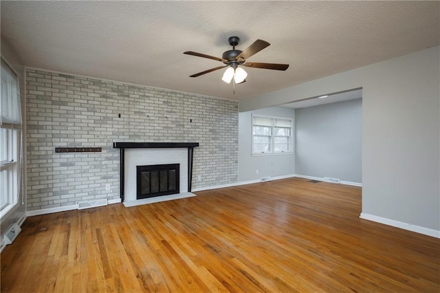 unfurnished living room with hardwood / wood-style flooring, ceiling fan, a fireplace, and a textured ceiling